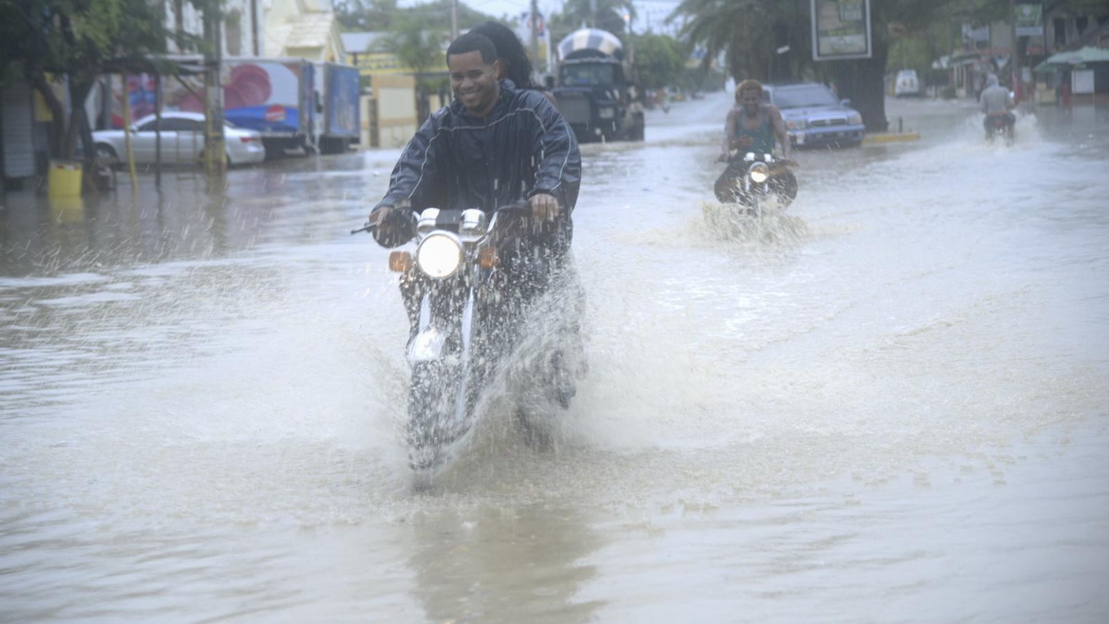 Un veí de la localitat de Villa Vásquez, a la República Dominicana, amb motocicleta per un dels carrers inundats. / LUIS TAVAREZ / EFE
