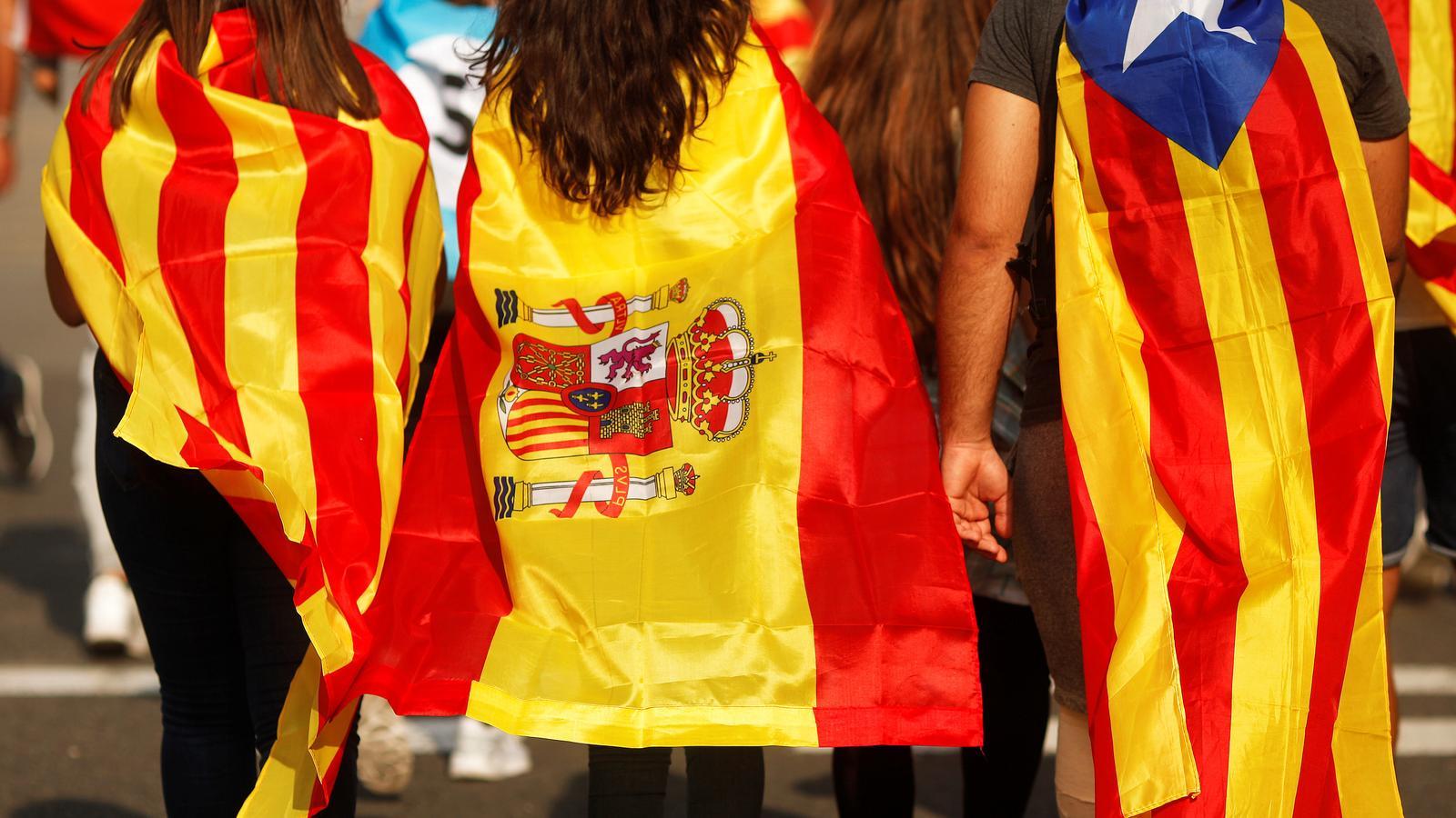 Tres joves vestits amb la bandera catalana, espanyola i l'estelada, a la manifestació contra la violència policial, el passat 3 d'octubre. / JON NAZCA / REUTERS