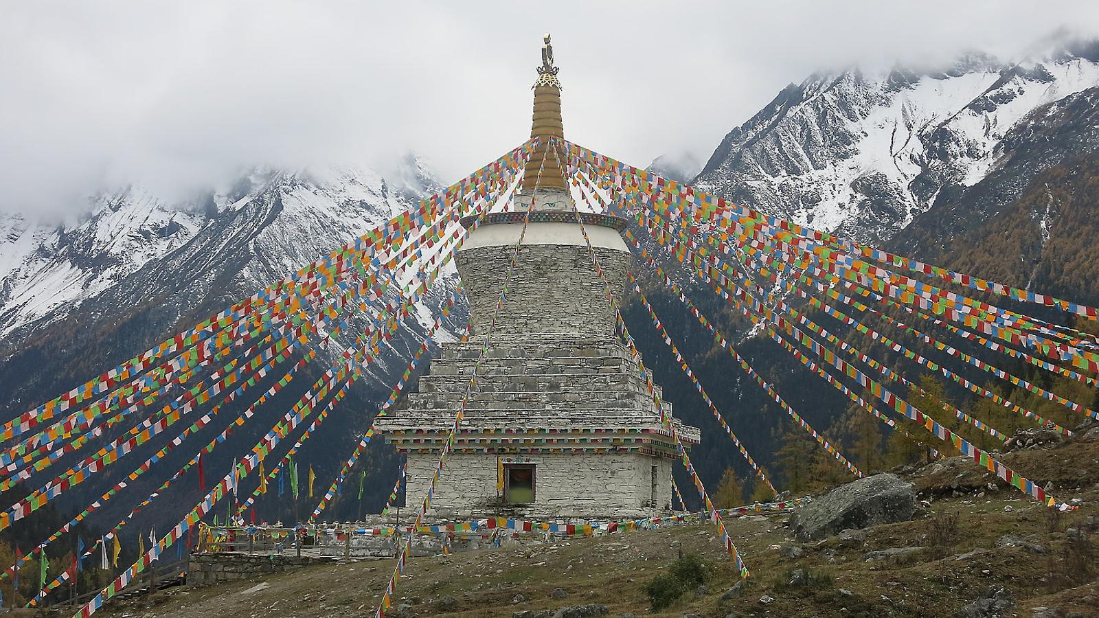 A dalt, una stupa amb banderes d’oració tibetanes, a les muntanyes Siguniang. A baix, monjos debatent a la porta del temple principal del monestir de Labrang.