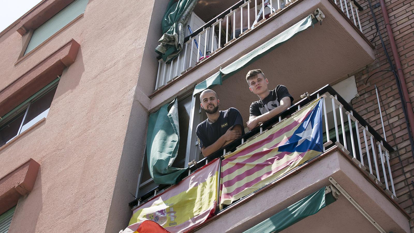 Els companys de pis Èrik i David al balcó de Badalona on tenen penjada una estelada i una bandera espanyola. / CRISTINA CALDERER