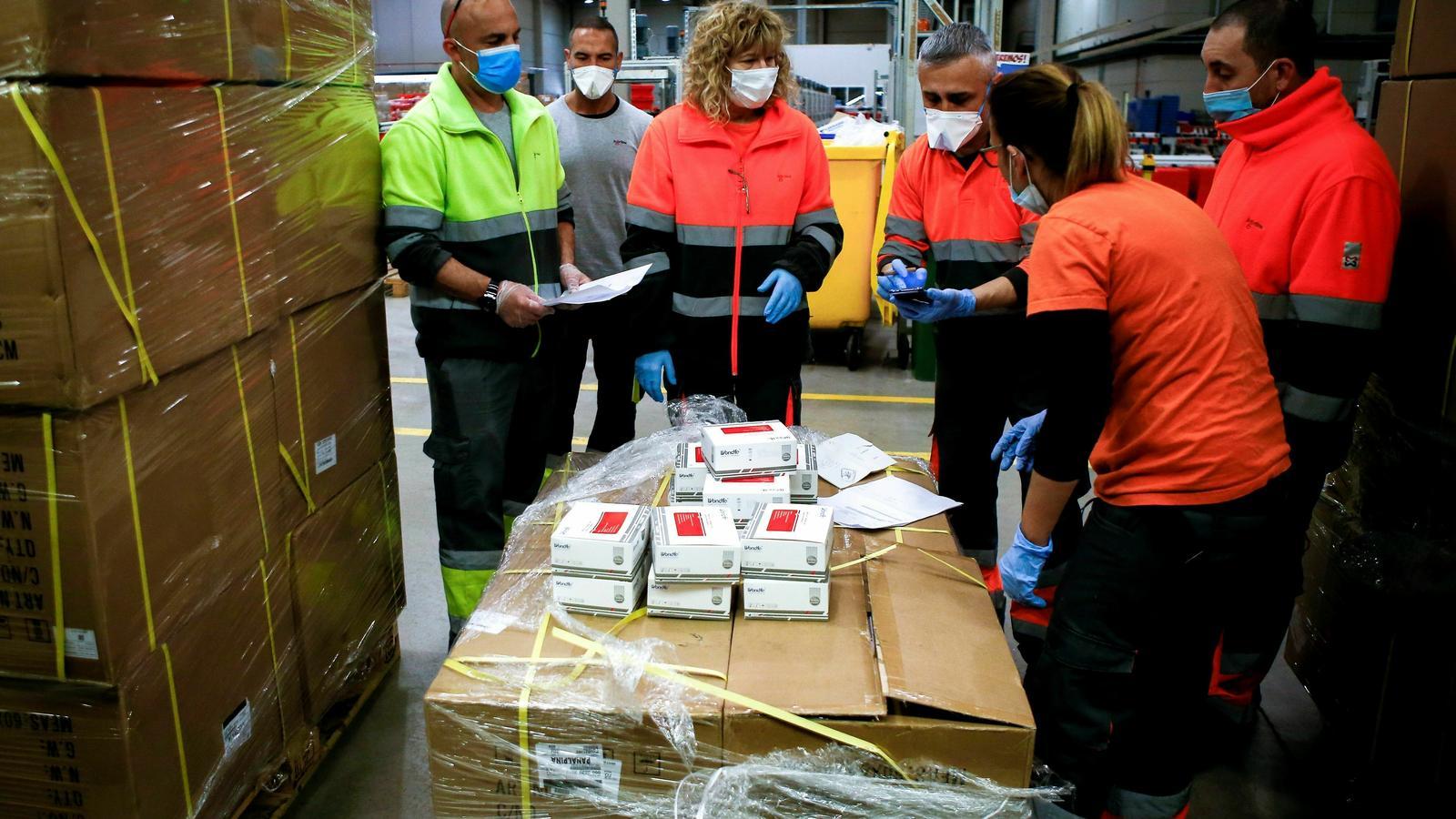 Treballadors de l'empresa Logaritme Servei Logistics IAE revisant el material sanitari a punt per ser distribuït a hospitals i residències de Catalunya / QUIQUE GARCÍA / EFE