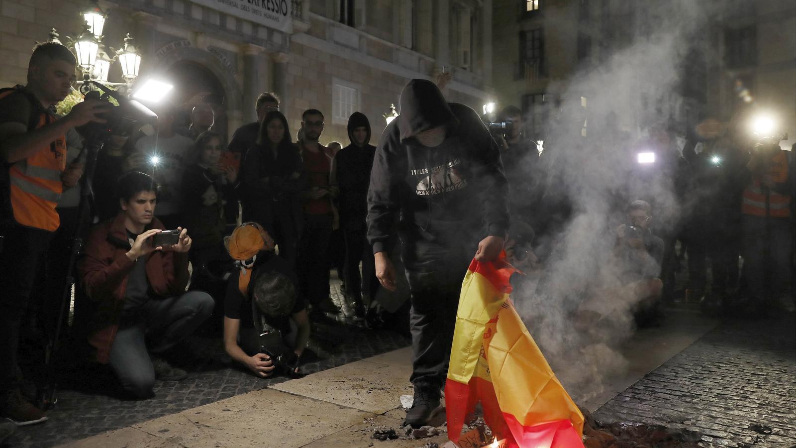 Un manifestante quema una bandera española en una protesta a laPlaça Sant Jaume de Barcelona / ANDREU DALMAU / EFE